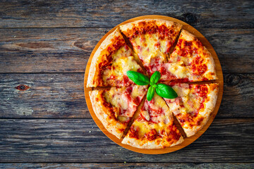 Pizza Serrano with cooked ham, mozzarella cheese and vegetables on wooden table
