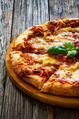 Pizza Serrano with cooked ham, mozzarella cheese and vegetables on wooden table
