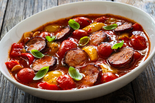 Delicious lecho - vegetables with sausages on wooden table
