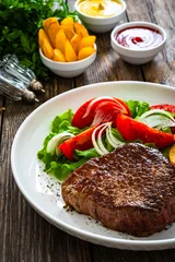 Foto op Aluminium Grilled beef steak with French fries and fresh vegetables on wooden table  © Jacek Chabraszewski