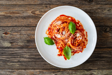 Spaghetti marinara - noodles with tomato sauce, parmesan cheese and basil leaves served on wooden table
