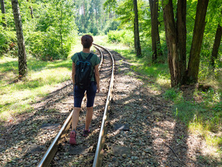 Attractive red hair girl backpacker walks on rails of narrow gauge Gablenz Kromlau, Germany - 642882497