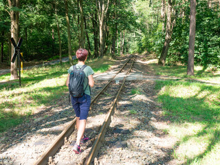Attractive red hair girl backpacker walks on rails of narrow gauge Gablenz Kromlau, Germany - 642882668