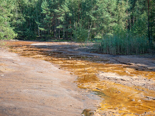 Colorful mud at stream flowing to poisooned lake i