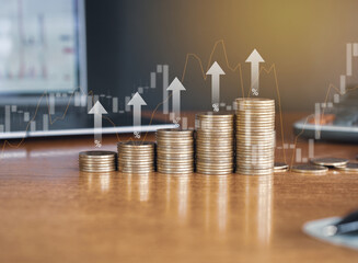 Up stack money coin with laptop computer and calculator in the background with trading graph and up arrow, Business and Financial concept. 