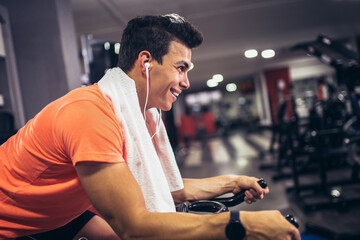Man biking in the gym, exercising legs doing cardio workout cycling bikes.