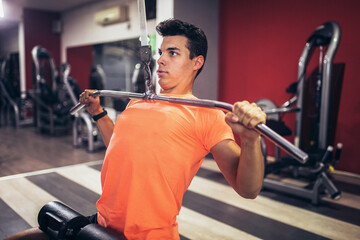 Fototapeta na wymiar Young handsome man doing exercises in gym