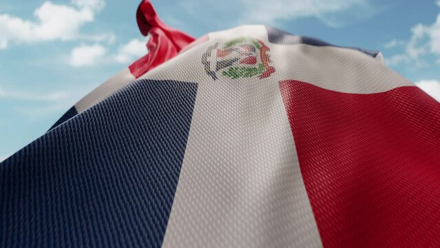 Wavy flag of Dominican Republic blowing in the wind in slow motion. Waving colorful flag team symbol abstract vertical background. Blue sky with clouds. World countries flying flags concept