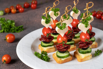 Canape with cheese, cherry tomatoes, sausage and black olives