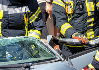 Feuerwehr im Einsatz, um in einem Auto eingeklemmte Person zu bergen. Firefighters in action to...