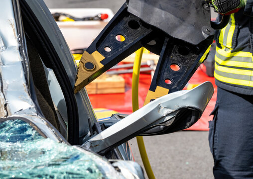 Feuerwehr in Aktion, um eine im Auto eingeklemmte Person zu bergen . Spreizer im Einsatz. Firefighters in action to rescue a person trapped in a car.
