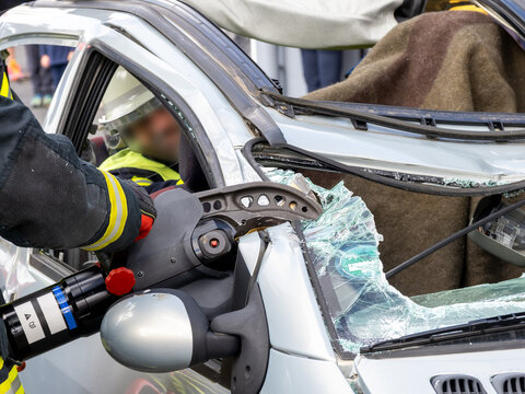 Feuerwehr im Einsatz, um in einem Auto eingeklemmte Person zu bergen. Durchtrennen der A-S&auml;ule mit Hydraulische Rettungsschere