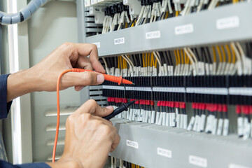 Electrical engineer using measuring equipment to checking electric current voltage at circuit breaker and cable wiring system , Electrical service concept .