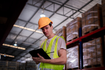 Industry warehouse worker in safety uniform check order details and checking goods supplies on boxes shelve in workplace warehouse industry logistic export import distribution business concept.	