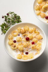 Breakfast with granola, berries and milk in small bowls on a white background