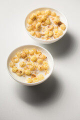 Breakfast with granola and milk in small bowls on a white background