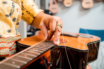 Young musician changing strings on a classical guitar in a guitar shop