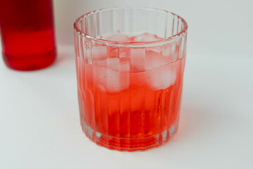 Red cocopandan flavored syrup in a glass with some ice. 