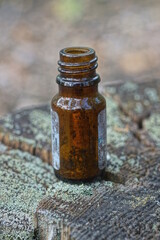 one old small brown glass open bottle stands on a gray wooden stump in the street