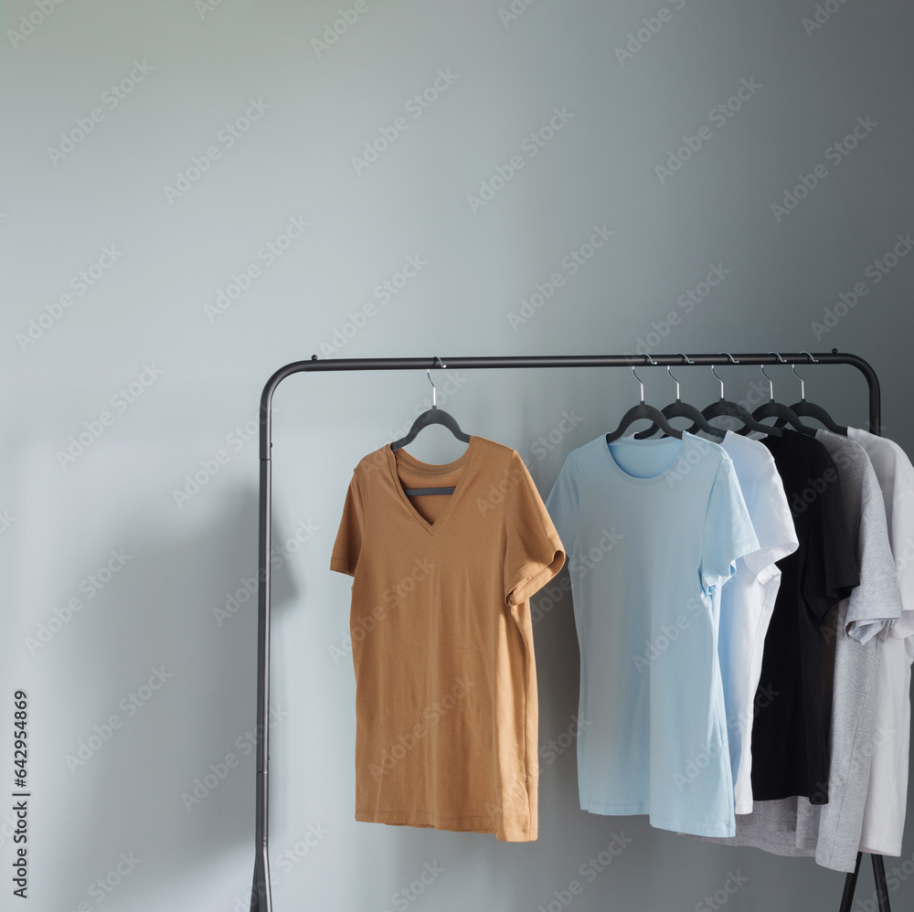 Wall mural T-shirts of neutral colors on  black hanger against  gray wall