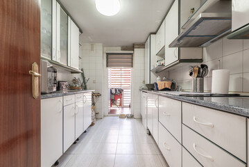 A kitchen furnished on both sides with white furniture