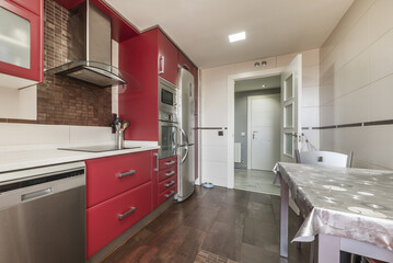 A kitchen with red wooden furniture and integrated