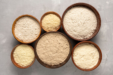 Set of organic flour in clay bowls on gray background