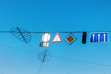 Road signs and traffic lights hang on wires against the background of the sky