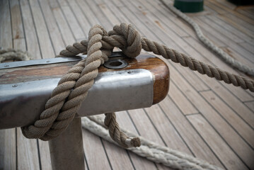 A ship's rope is tied to a rig against the background of a sailboat deck