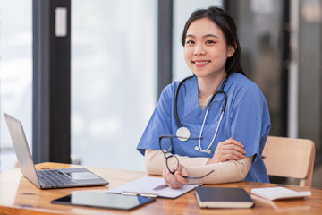 Fototapeta na wymiar Portrait of Young Asian smiling female nurse working on laptop in private clinic, Positive emotional and good moment.Health Care Concept.