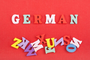 German word on red background composed from colorful abc alphabet block wooden letters, copy space for ad text. Learning english concept.