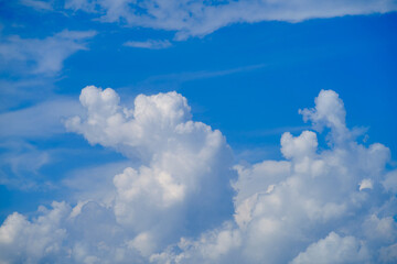 The cloudscape against the blue sky was illuminated by the bright sunlight of the summer day.