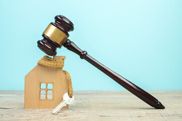 Wooden house, keys and judge's gavel on a wooden table. Symbol of mortgage or dilapidated housing...