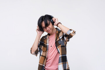 A young asian man listening to great tunes on his wireless headphones.Immersed and captivated to...