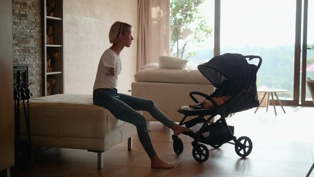 Mother living with Phocomelia syndrome, rocking her baby to sleep in a stroller with legs