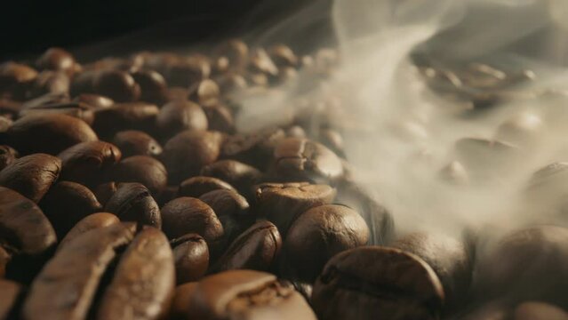 Roasting coffee beans with smoke on dark background. Smoke comes from fresh coffee seeds. Slider Macro shot, 4K