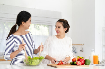 healthy eating, family friendship and people concept - Female Friends Enjoying Fresh Salad in kitchen and Having Fun. cooking vegetable salad for dinner at home kitchen