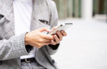 Unrecognizable businesswoman holding modern smartphone using mobile business application outdoors