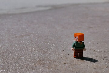 Obraz premium LEGO Minecraft figure of Alex standing on crystallic salty field, remains of fifth stage of sea salt production, looking left. 