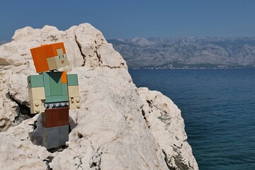 Obraz premium LEGO Minecraft action figure of main female character Alex standing on rocky beach of Radanovac in northern Dalmatia, near town of Razanac. Velebit mountain in background. 
