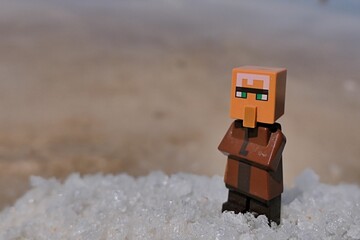 Obraz premium LEGO Minecraft figure of Villager mob standing on pile of salt next to sea salt production field.