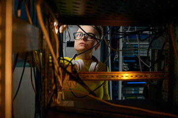 Young woman IT engineer working in datacenter room connecting cables