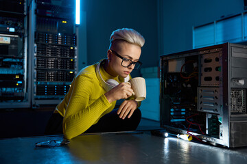 Young IT technician taking break drinking coffee in serve room
