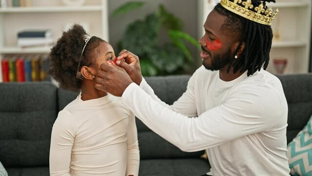 African american father and daughter wearing king crown and baggy eyes pad at home