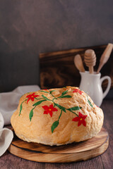 Loaf of bread hand painted with edible paints on a wooden board vertical view