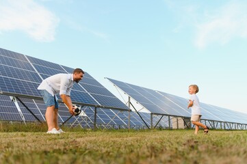 A father and his little son play football near the solar panels. The concept of renewable energy.
