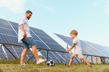 Father and son playing football in garden of solar paneled