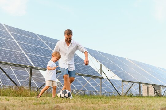 Father and son playing football in garden of solar paneled