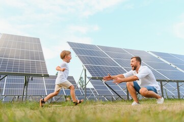 Smiling father and his little child on background of solar panels. Young father enjoy spending time...