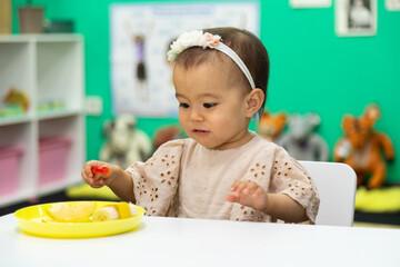 Toddler eating cut fruits and vegetables in the plate